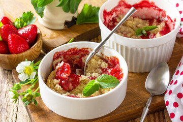 Summer dessert home cooking close-up. Strawberries crumble in a baking dish and fresh strawberries on a wooden rustic table.