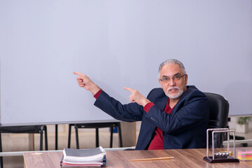 Old teacher physicist sitting in the classroom