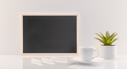 Modèle de tableau noir en ardoise avec espace vide pour logos, inscription publicitaire. Cadre en mode paysage sur un espace de travail avec une tasse et des craies.