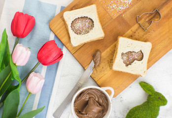 Fototapeta na wymiar Sandwiches with chocolate in the form of a rabbit and eggs on a wooden board. Easter children's lunch. Festive dinner for children. fun food art.