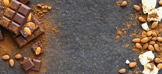 Dark chocolate pieces crushed and cocoa beans, almond culinary background, top view