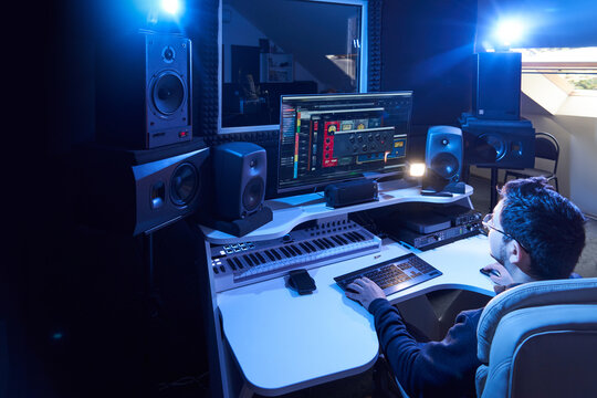 Professional male sound engineer mixing audio in recording studio. Music production technology, working on mixer