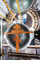 An Orthodox wooden cross, prepared for the consecration of water, lies on a bowl. Holy Epiphany, Jordan. Consecration of water. The concept of Orthodoxy.