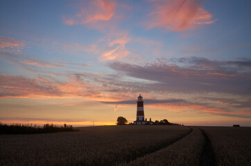 Dramatic sunset colour in the sky on the Norfolk coast at Happisburgh with the iconic lighthouse in the distance