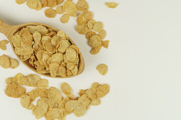 Wooden spoon with cornflakes on white background