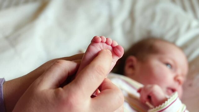 Demonstration of the baby's reflex. Mom presses her toe on the foot, the fingers clench and unclench. Foot massage for a child.