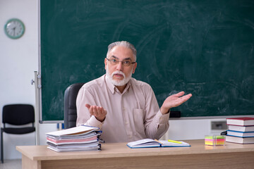 Old male teacher sitting in the classroom