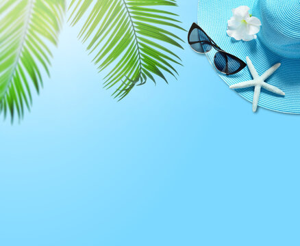 Tropical summer beach background. Palm trees branches, hat with starfish on blue summer background. Travel. Summer concept.