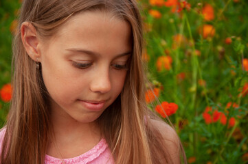 Naklejka premium Outdoor portrait of cute girl in summer day. Portrait of a blue-eyed girl with flowers in the background.