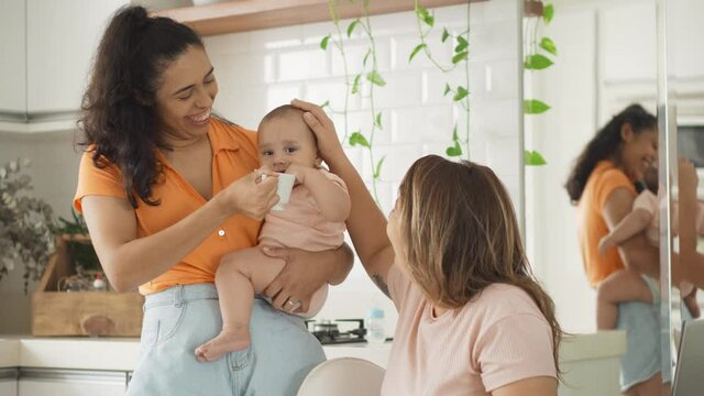 gay couple with a thirsty baby trying to drink water in the kitchen
