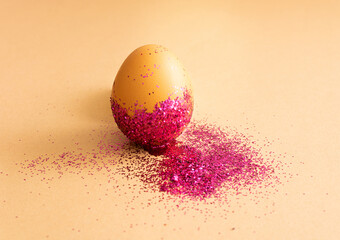 Creative festive scene with an egg in center overlaid with purple glitter on beige background....