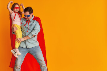 serious father with a beard, a superhero holding a little baby girl, together dressed in superman...