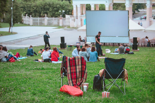 People Resting At Public Park Watching Movie At Open Air Cinema