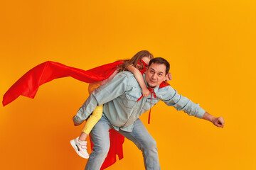 serious father with a beard, a superhero holding a little baby girl, together dressed in superman...