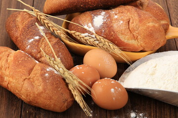 Delicious breads next to ears of wheat on a wooden board. Bakery products.