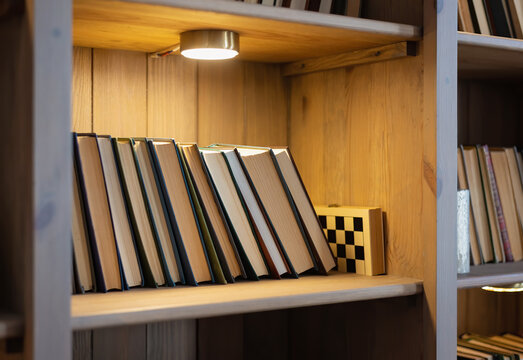shelf with books in the bookcase lit by a lamp