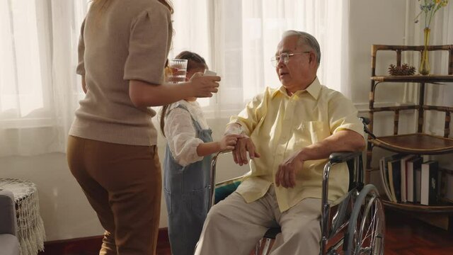 Grandfather and daughter share time together at home. Senior man Taking Pills Medicine. granddaughter take care older with love. Caretaker, Retirement, Caregivers at Home, Medicine and health care.