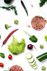 Round raw veal burgers with various vegetables and herbs. Grocery background for flat lay. Layout