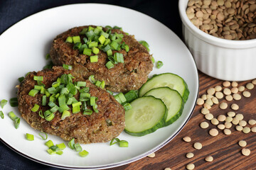 Lentil cutlets garnished with green onions and cucumber on rustic wooden table, closeup, vegetarian lenten eastern dish, healthy vegan food concept