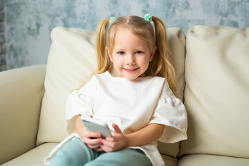 beautiful little girl on the couch with a mobile phone