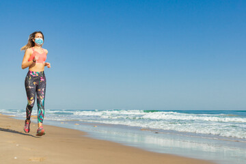 Girl running sport in the beach with covid mask and a blue sky and a blue sea with whit waves.