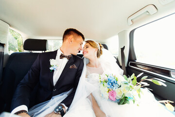 Close-up portrait of newlyweds kissing in the back seat of a car.