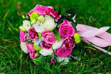 wedding bouquet lying on green grass, white, pink and green flower in a bouquet.
