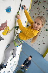 Hübsche, nette, freudliche Jungen und Mädchen beim Klettern, Bouldern. Die Kinder, 8 bis 12 Jahre alt, freuen sich Hallensport zu treiben und auszutoben. Fitness, Gesundheit, Spass für die Familie.