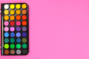 watercolour paints palette, top view on a pink background. Copy space for text