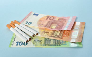 Cigarettes and money on blue background. Euro banknotes and coins, cost of smoking, cigarette price...
