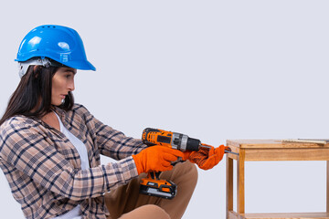 Female carpenter drills a hole with an electrical drill. Repair and renovation concept. Woman repair tools for house constructor. Cordless drill, screwdriver with drills