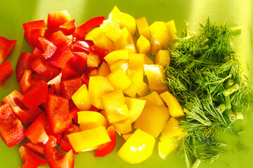 healthy sliced raw vegetables, red and yellow peppers and green parsley on a cutting board