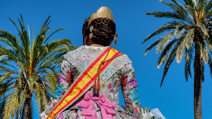 A young girl in festive clothes looks at the bright blue sky. The Fallas Festival is the most famous Spanish holiday, which is held in March in Valencia, Spain.