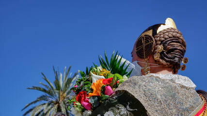 A young girl in festive clothes with a bouquet of flowers  looks at the sky. The Fallas Festival is the most famous Spanish holiday, which is held in March in Valencia, Spain.