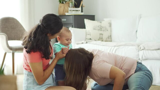 gay couple playing and having fun with baby in the living room
