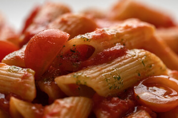 Penne with tomato sauce and cherry tomatoes macro close up