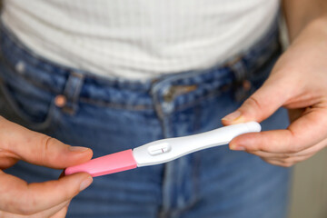 Young woman holding negative pregnancy test,home pregnancy test showing negative result close up