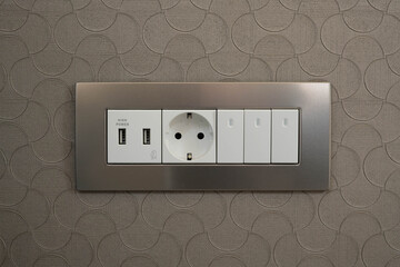 A 220 volt Euro standard socket with grounding in a metal frame and a USB charging socket and three switches.
