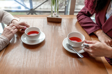 Cups of black tea in the hands of men and women. on a wooden background. with copy space. top view