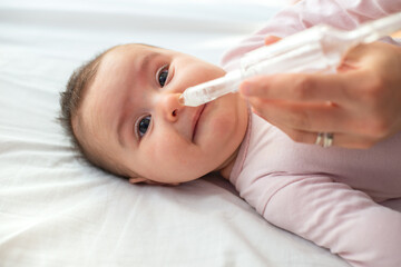 mother using baby nasal aspirator mucus nose suction