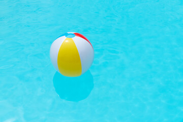 Beach Ball Floating on water surface of a swimming pool. Summer background. Copy space