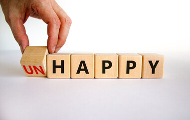 Be happy, do not unhappy symbol. Businessman turns the wooden cube and changes the word 'unhappy'...