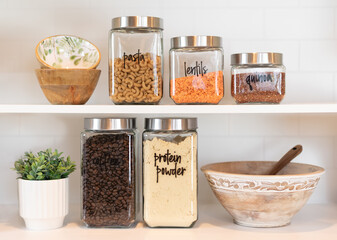 Dry food ingredients in glass jars on a kitchen shelf - 421343217