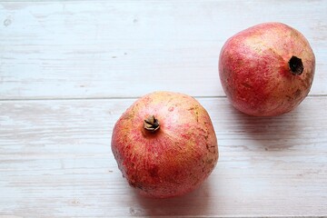 Fototapeta na wymiar two handsome pomegranates, red fruit, pomegranates on a light wooden background, pomegranates