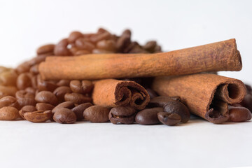 Coffee grains and cinnamon sticks on white. Defocus. Close-up.