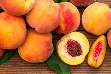 Ripe peaches and leaves on wooden table. Fresh fruits peaches with leaves on a wooden background