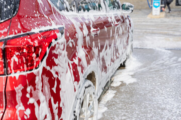 washing car at autowash . Car wash. red machine under the pressure of water at a car wash. Red car in foam