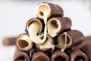 milk filling flows out of waffle tubes in chocolate