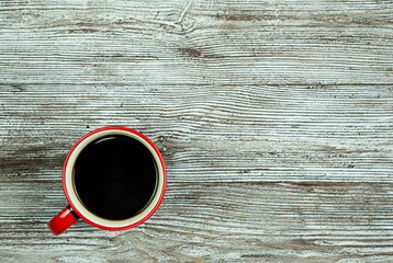 Red cup with espresso coffee on a brown wooden background.