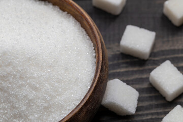 Obraz na płótnie Canvas White, crystalline granulated sugar and white cube sugar. Sugar is a harmful food to the body. Excessive consumption reveals diabetes and accelerates weight gain. 